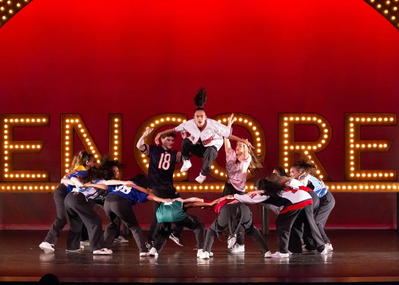 Hip hop dancers in red jerseys performing on stage